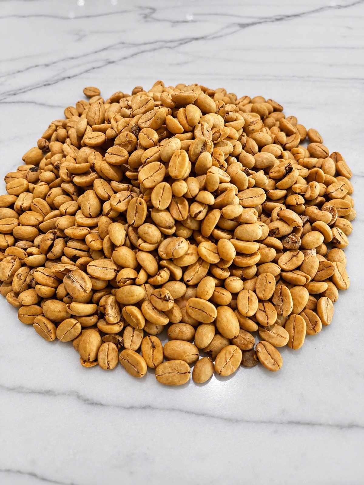 A pile of green coffee beans dried and retained in parchment